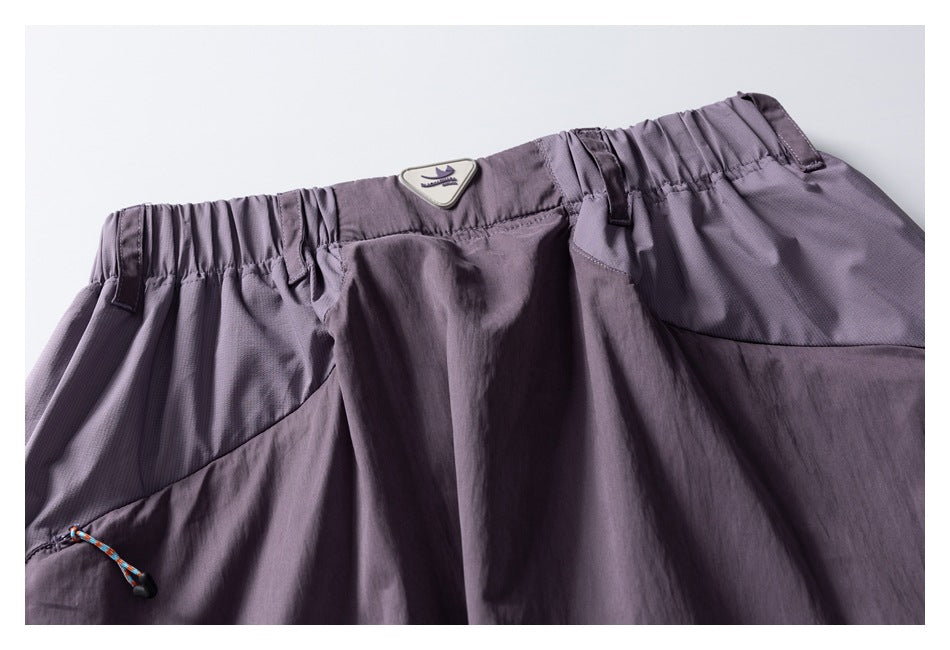 Close-up of lavender pants showing the elastic waistband, belt loops, pocket, drawcord, and sewn-on badge.