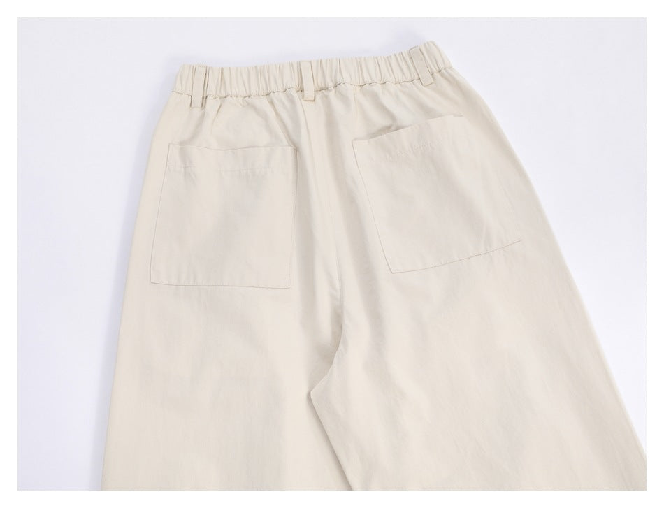 Back view of ivory wide-leg trousers with an elasticated waistband and two patch pockets.