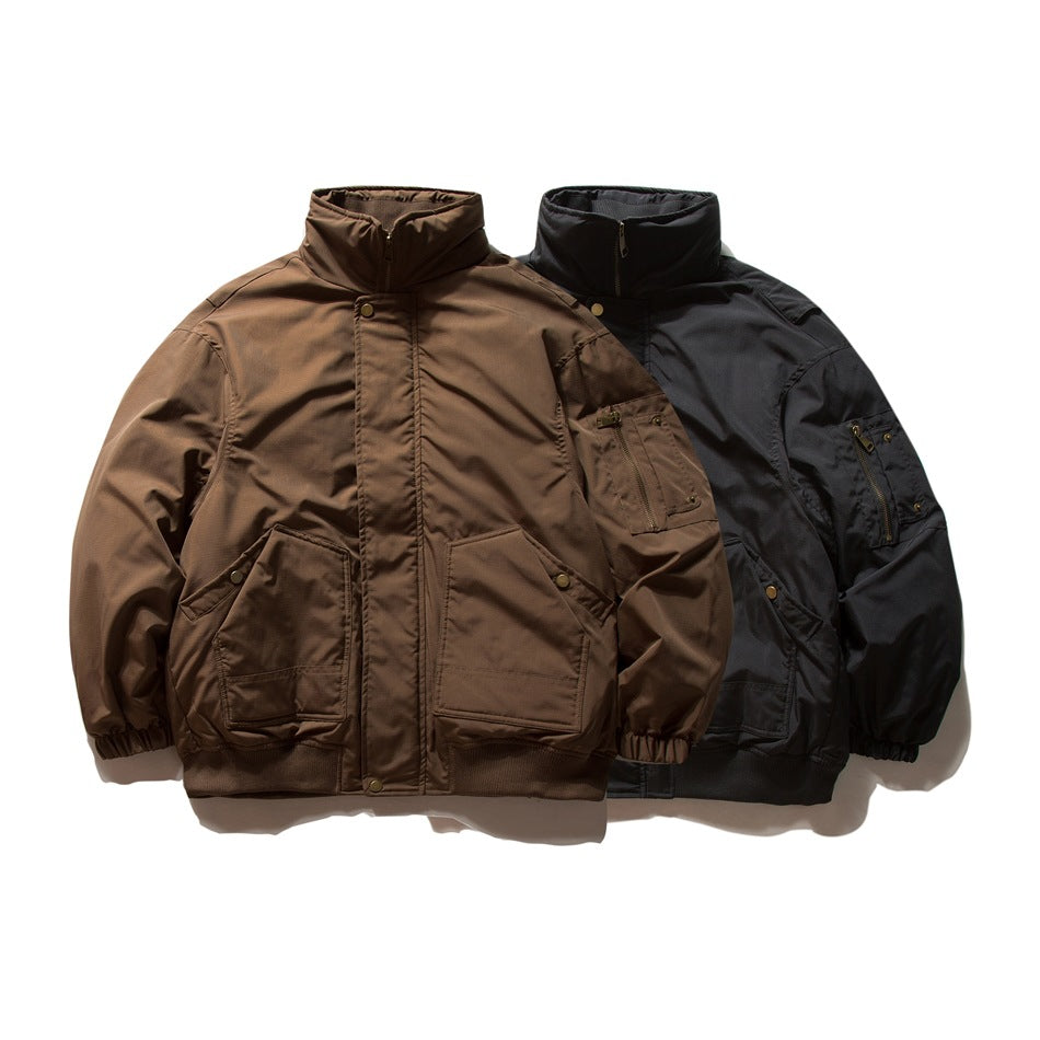 Brown and black zip-front jackets with high collars, snap storm flaps, front pockets, and sleeve pockets, shown from the