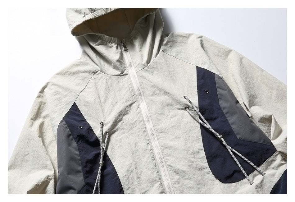 Cropped front view of an off-white hooded jacket with navy and gray panels, a white zipper, and hanging cords.