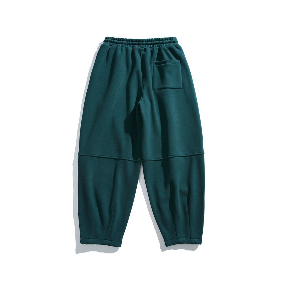 Back view of dark teal relaxed-fit joggers with an elastic waistband, rear patch pocket and paneled legs.
