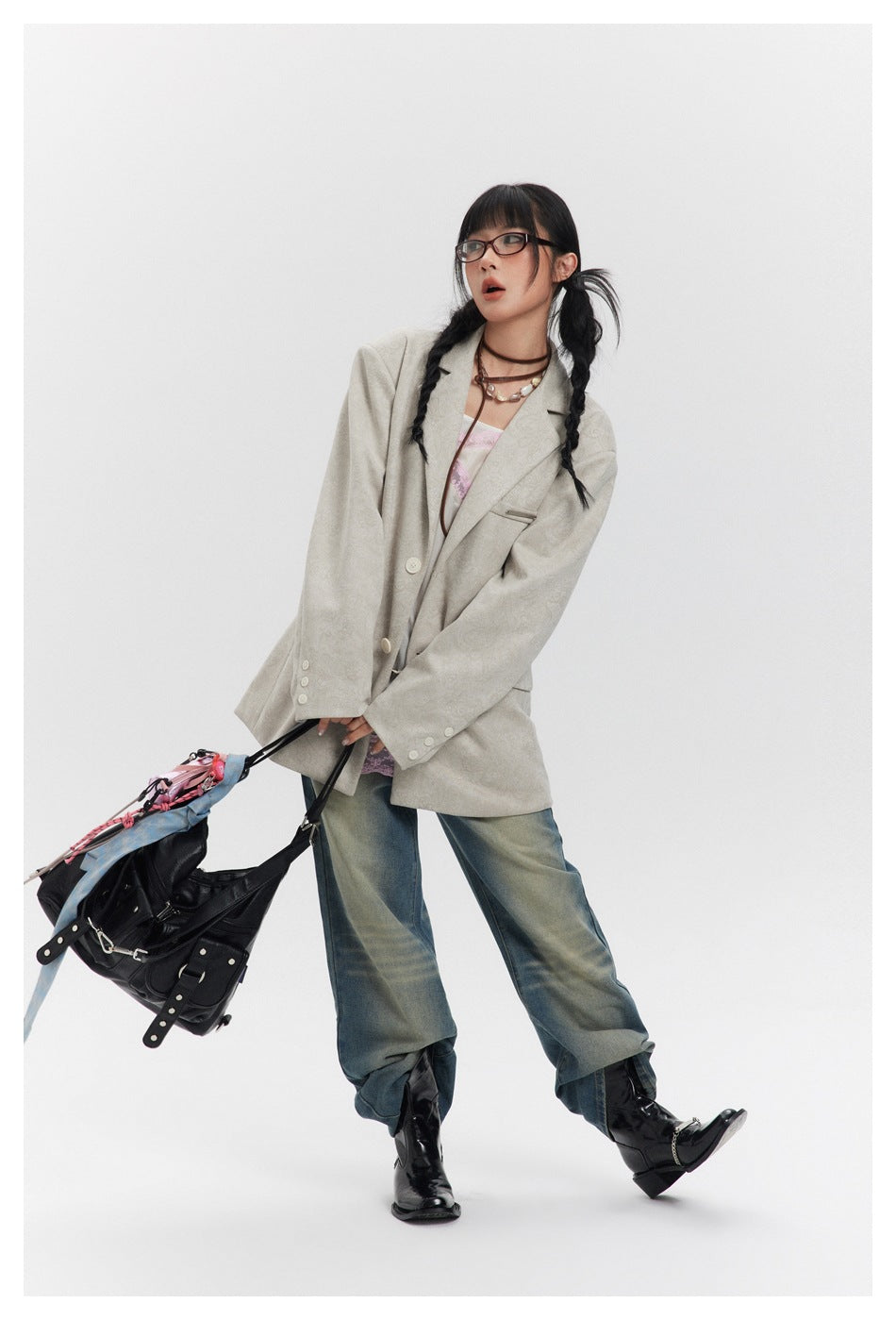 Model wearing the oversized beige patterned blazer jacket with jeans, boots and a black bag in a dynamic pose