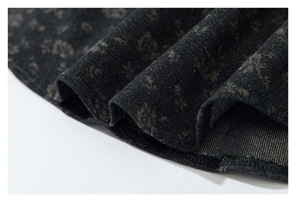 Close-up of the dark garment's patterned fabric and stitched hem edge.