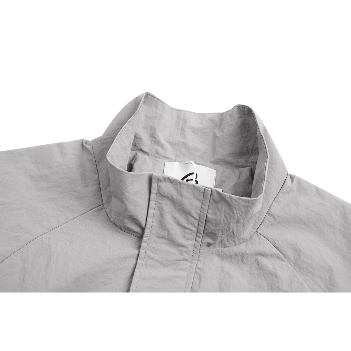 Close-up of a light gray jacket's stand collar and front placket, with a small sewn-in neck label.