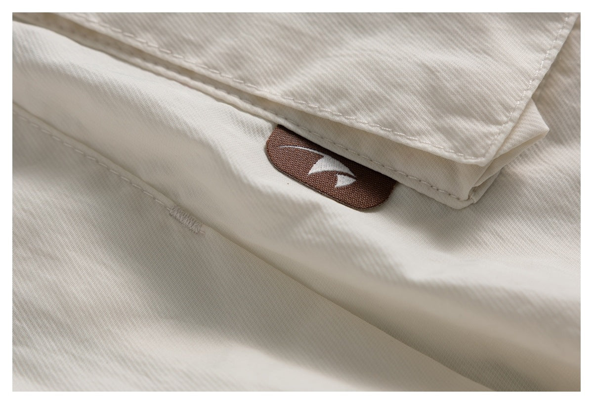 Close-up of an ivory garment seam and flap with a brown fabric patch bearing a white symbol.