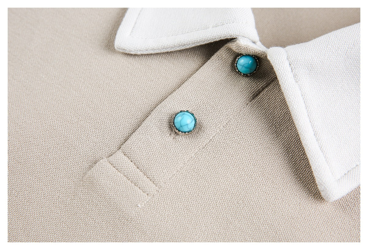 Close-up of a beige knit garment with a white collar and turquoise buttons.