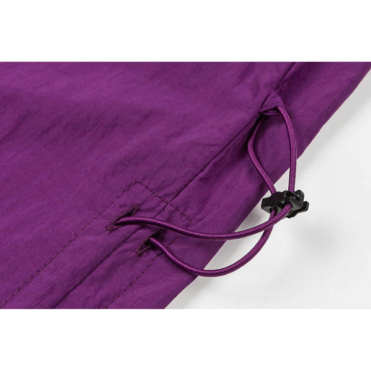 Close-up of a purple skirt's side hem drawcord and black cord lock.