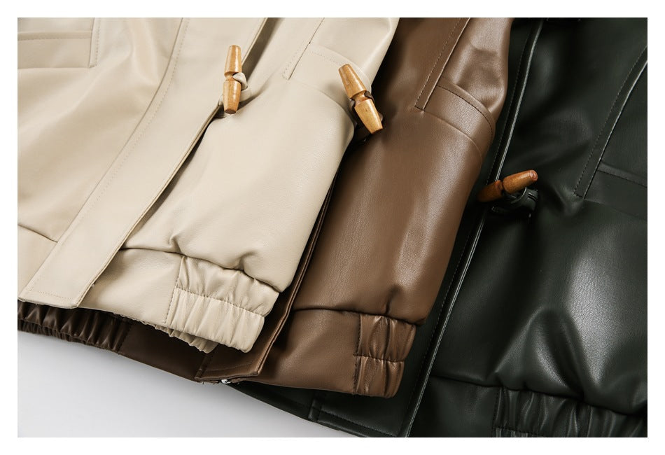 Cream, brown, and dark-green jackets arranged together, showing wooden toggle closures, sleeves, and elastic hems.