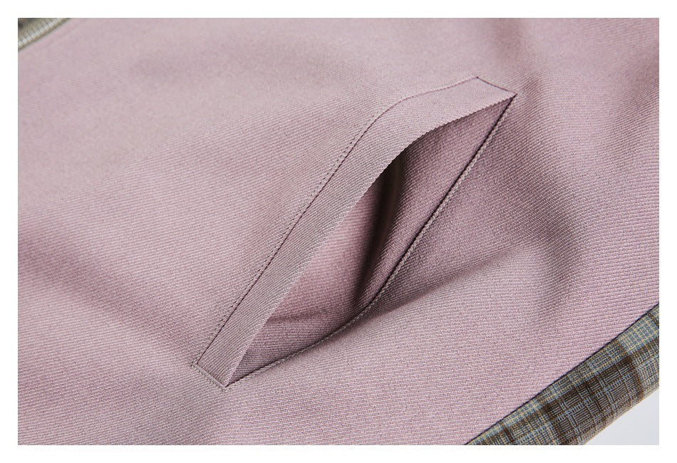 Close-up of a slanted welt pocket on a mauve jacket panel, bordered by brown plaid fabric.