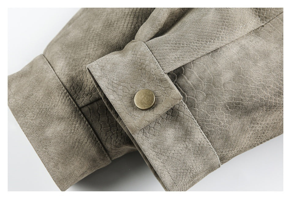 Close-up of a taupe textured jacket cuff with a brass-tone snap button and stitched tab.