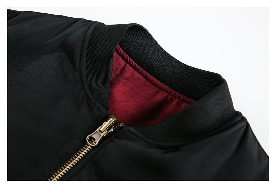 Close-up of a black jacket collar with burgundy lining and a brass-tone front zipper.