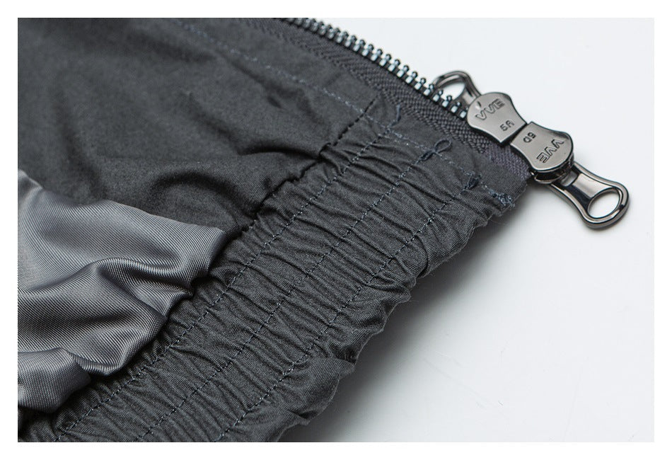 Close-up of a dark gray garment seam and lining beside a black zipper with metal pulls.