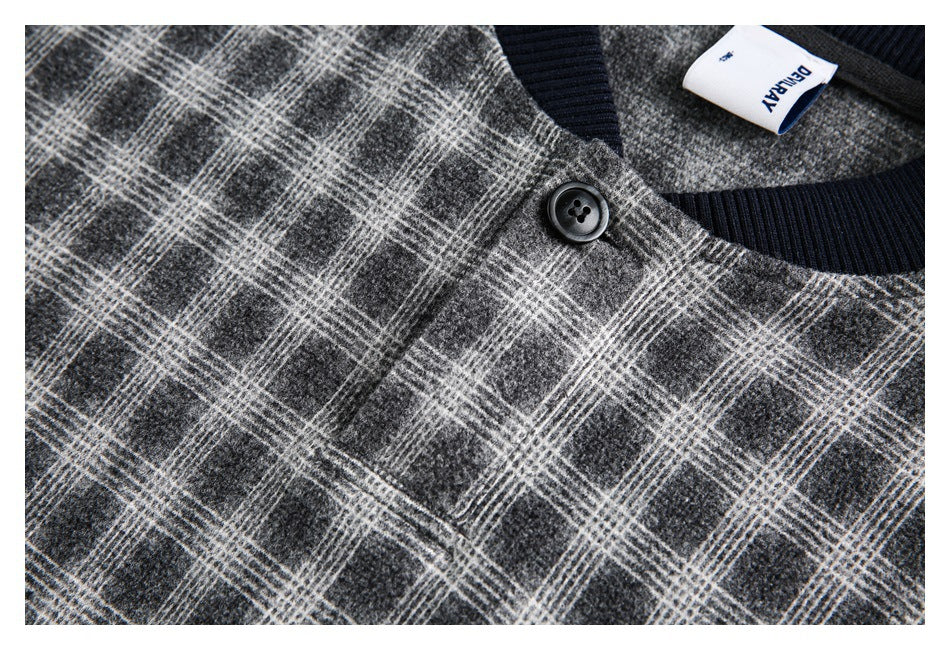 Close-up of a black button and navy ribbed neckline against gray plaid jacket fabric.