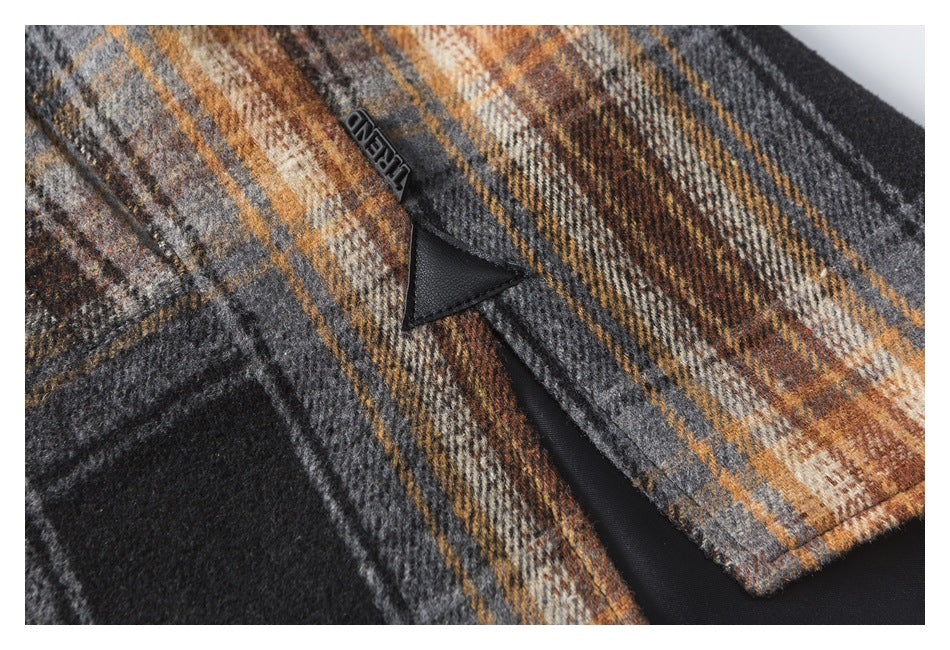 Close-up of a black zipper pull and dark zipper on a charcoal, cream, and rust plaid garment.