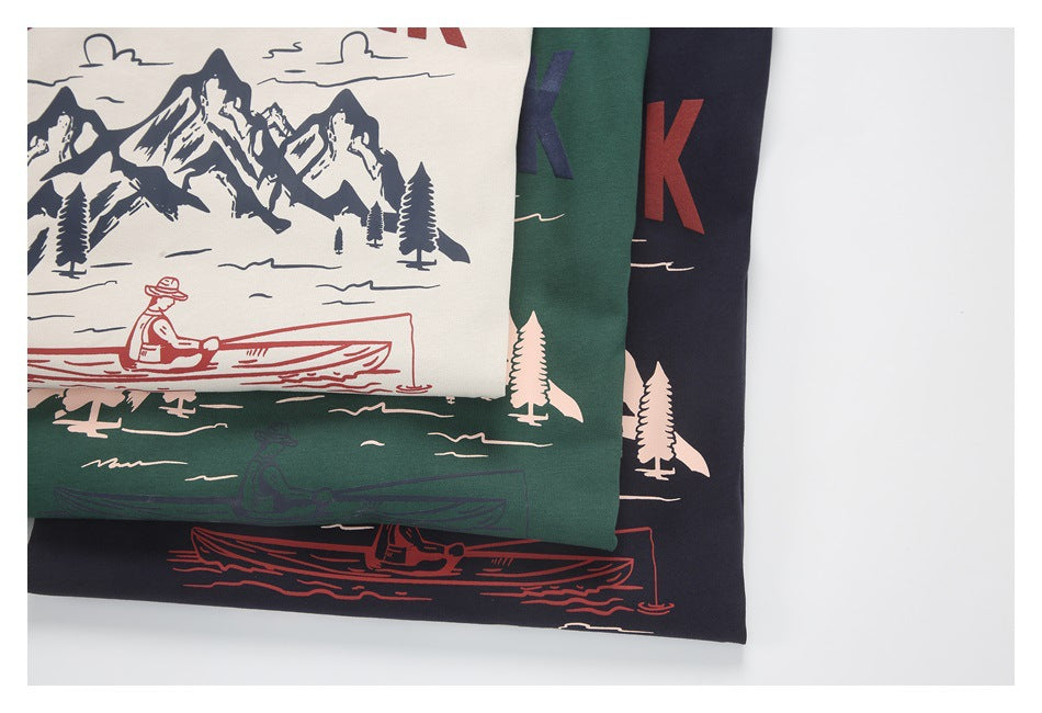 Close-up of three folded shirts showing mountain, tree, and canoe prints in contrasting colors.