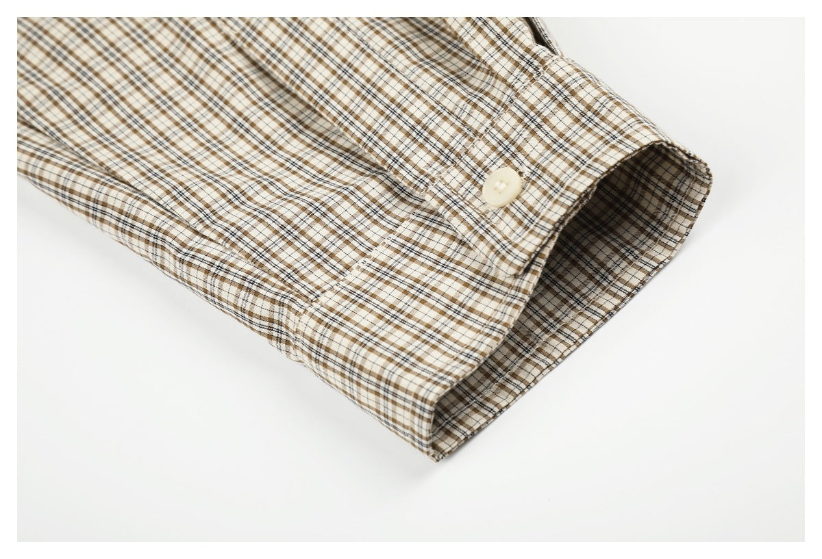 Close-up of a plaid sleeve cuff with a cream button against a white background.