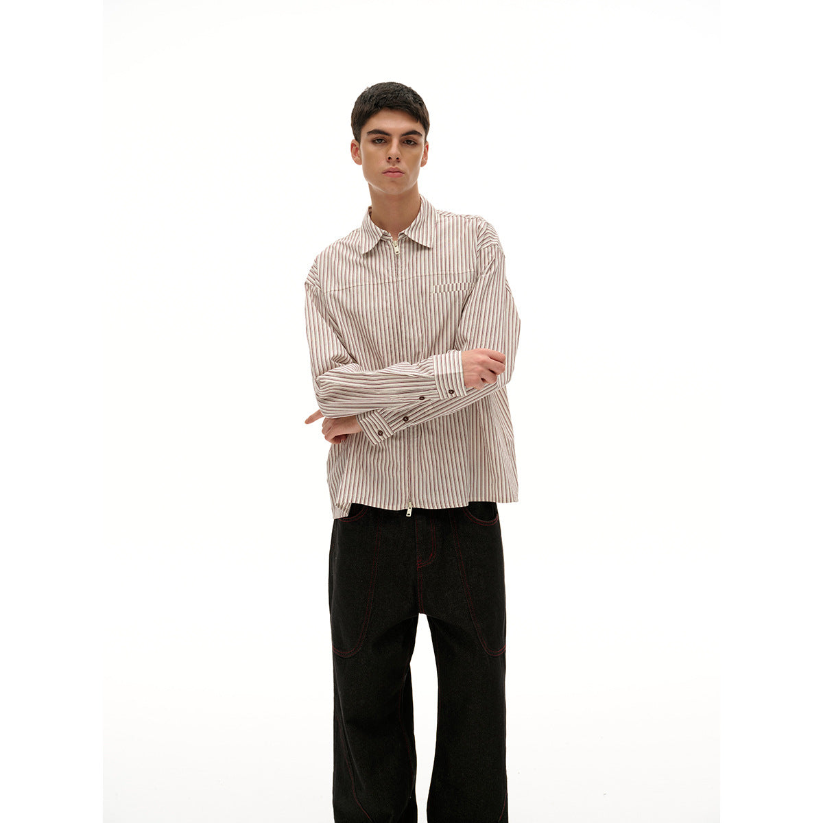 Closer view of a model wearing a red-and-white pinstriped zip-front shirt and wide black jeans.
