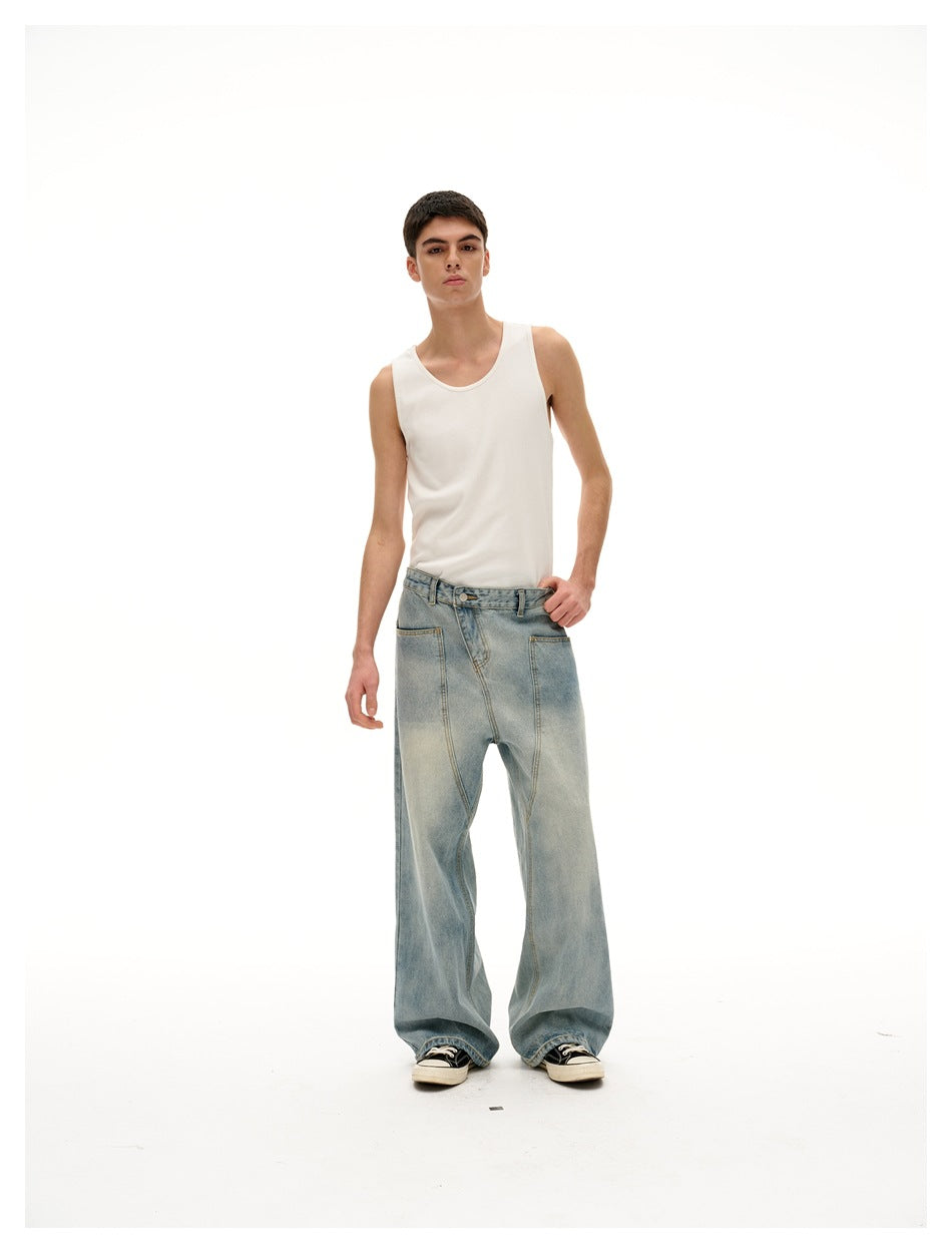 Model wearing washed blue wide-leg jeans with a white tank top and black sneakers, standing with a hand on hip