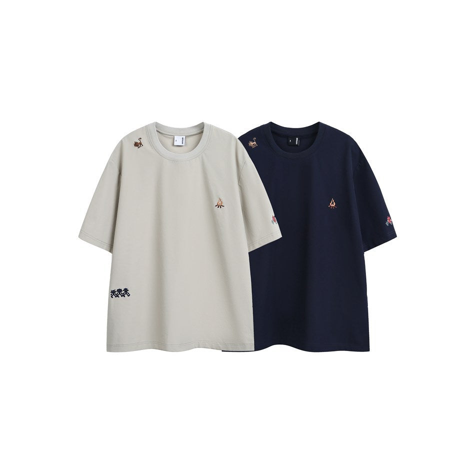 Beige and navy short-sleeve crew-neck T-shirts shown from the front, each with small embroidered motifs.