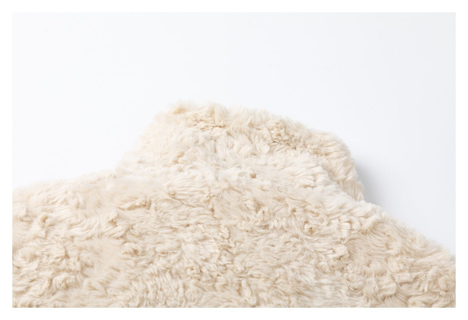 Close-up of the upper section of a cream shaggy garment against a white background.