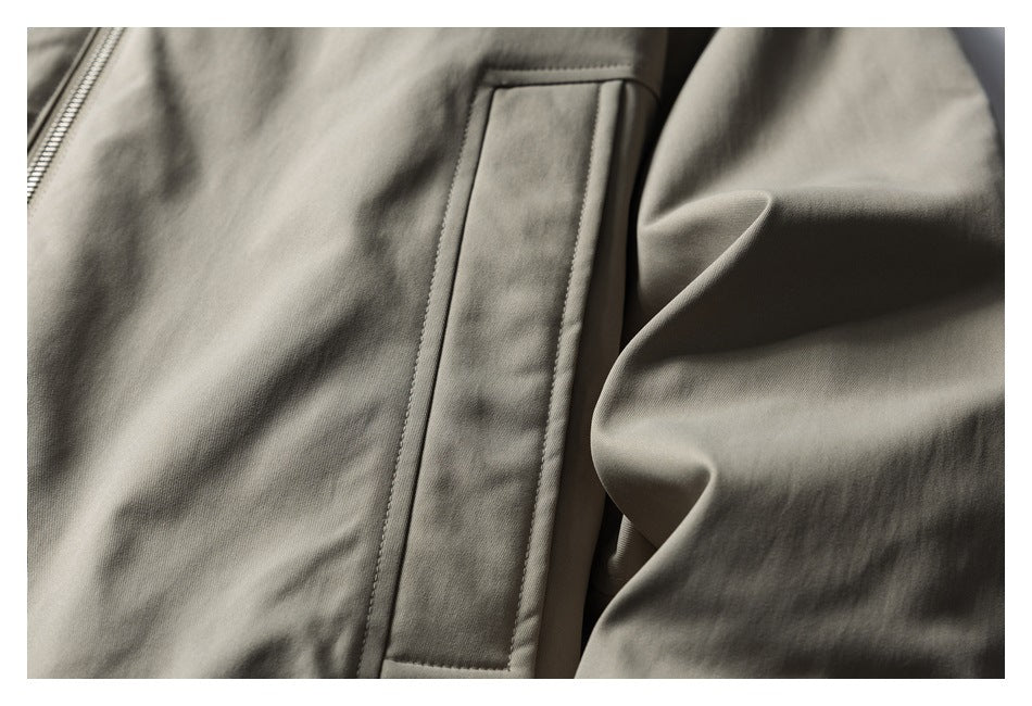 Close-up of a taupe garment's pocket beside a visible zipper.