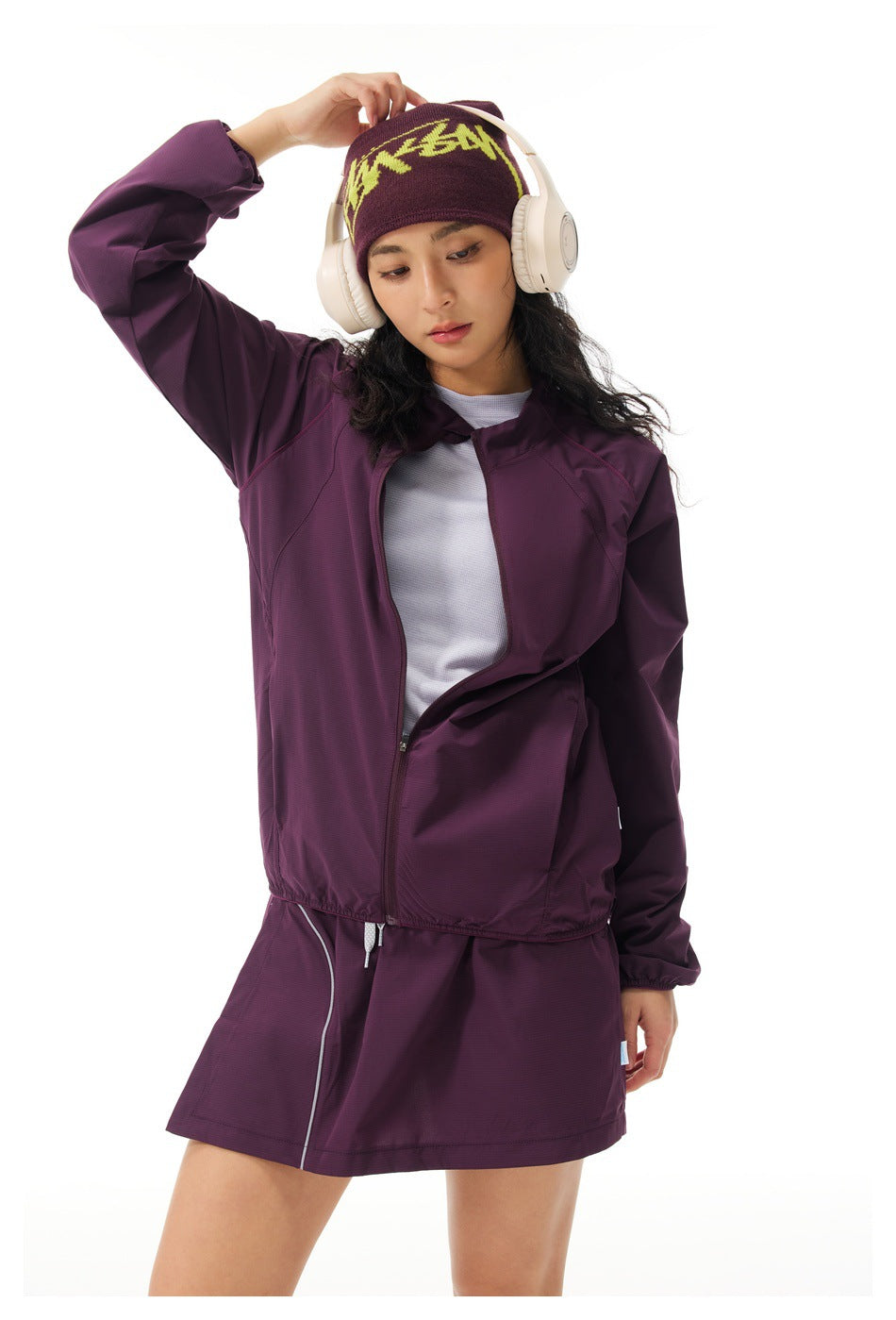 Model wearing an open plum jacket over a light shirt with a matching skirt.