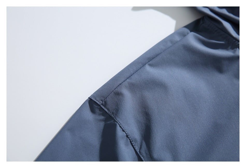 Close-up of a stitched seam on the slate-blue jacket against a white background.