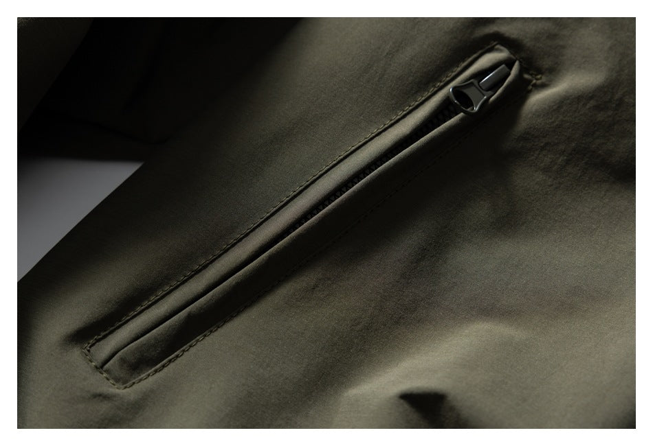 Close-up of a diagonal zip pocket and zipper pull on olive green jacket fabric.