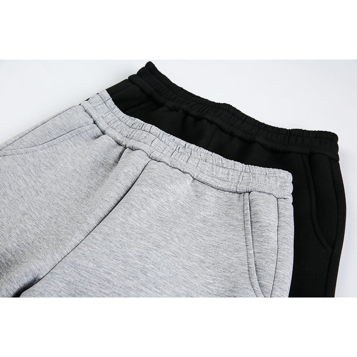 Close-up of gray and black pants showing elastic waistbands and front pocket openings.