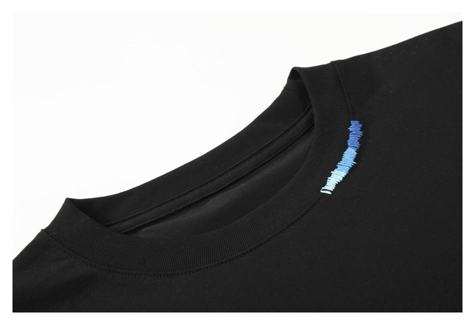 Close-up of a black T-shirt's ribbed crew neck and small blue embroidered detail near the collar.