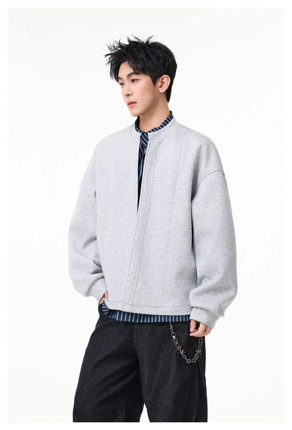 Three-quarter view of a model wearing a light gray oversized jacket with a stand collar and dropped shoulders.
