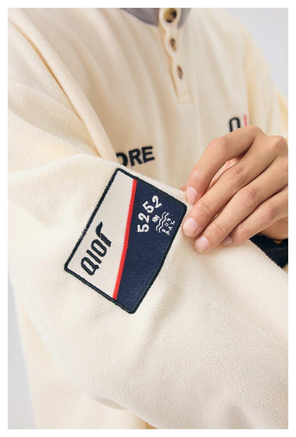 Close-up of a sewn navy, white, and red patch on the cream pullover sleeve.
