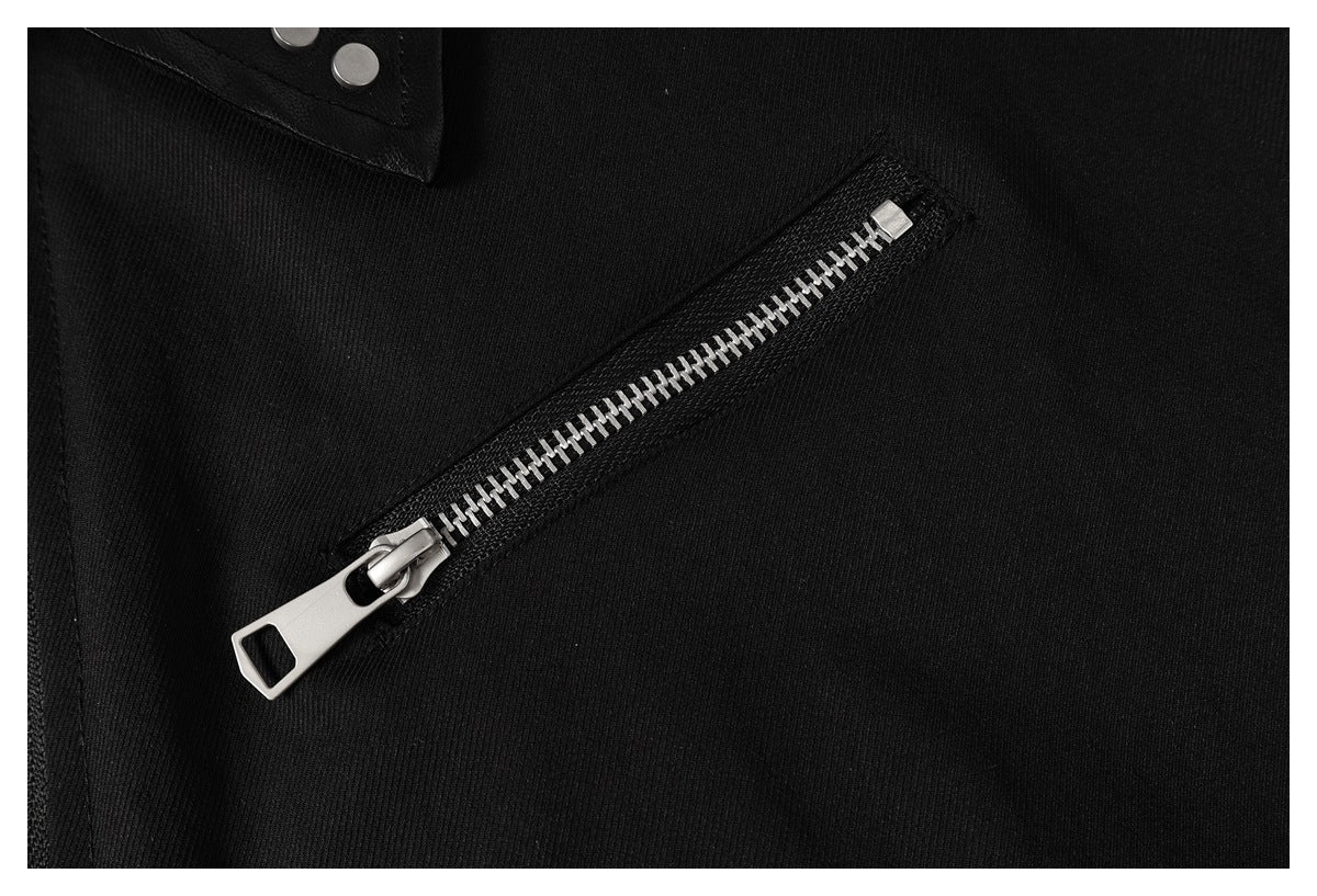 Close-up of a black garment with a diagonal silver zipper and snap-fastened tab.