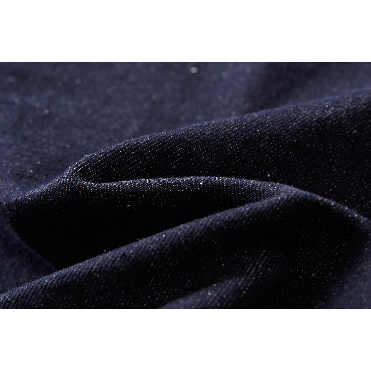 Macro view of dark indigo denim fabric folded to show its woven texture.