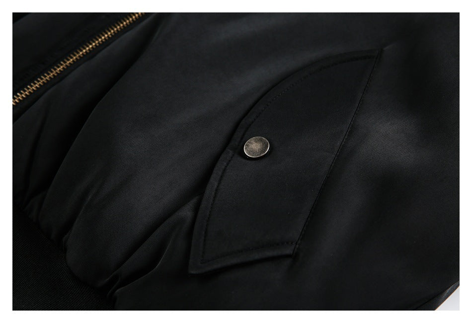 Close-up of a black jacket pocket flap secured with a round metal snap.