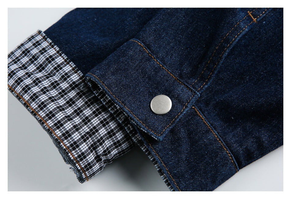 Rolled dark denim cuff showing black-and-white check lining, orange stitching, and a silver snap.