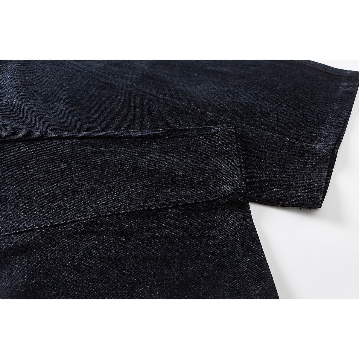 Close-up of dark pants showing overlapping fabric panels and stitched seams.