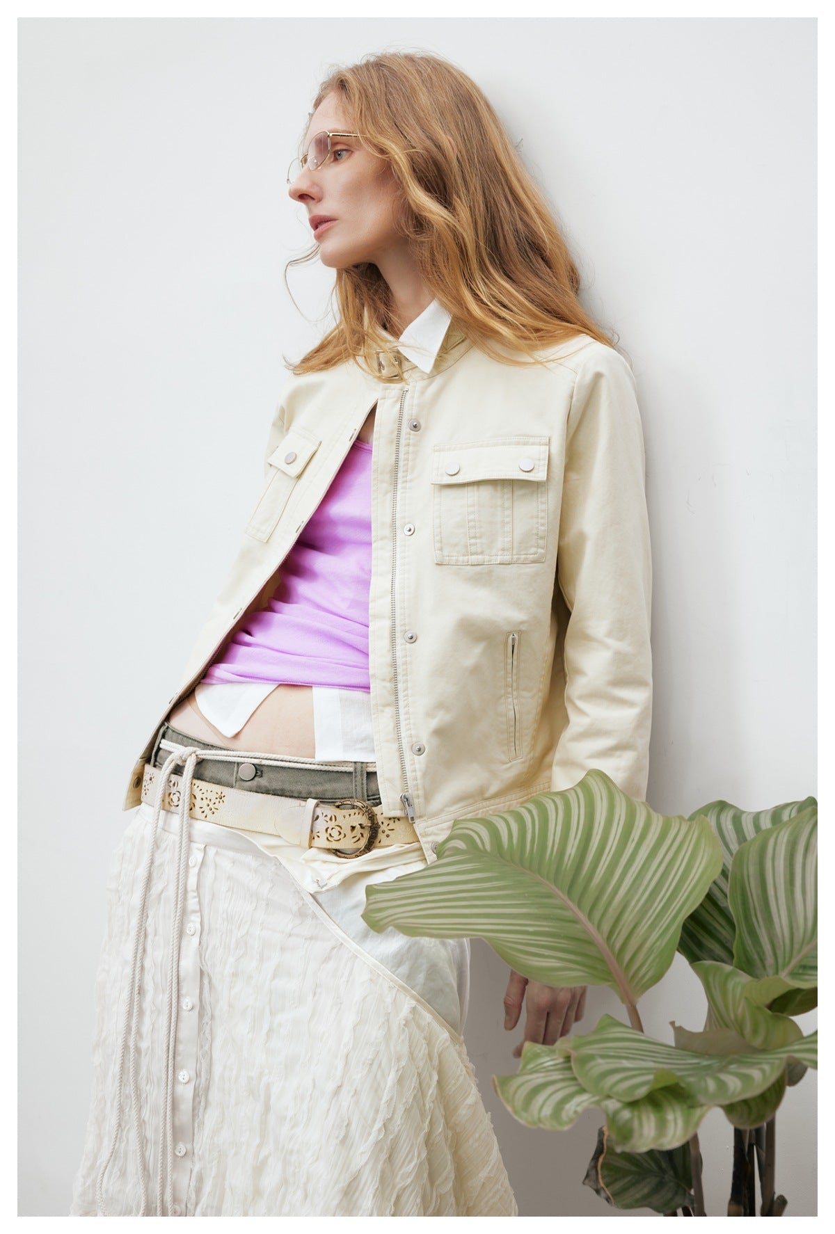 Close side view of a model wearing an ivory utility jacket with flap pockets over a lilac top.