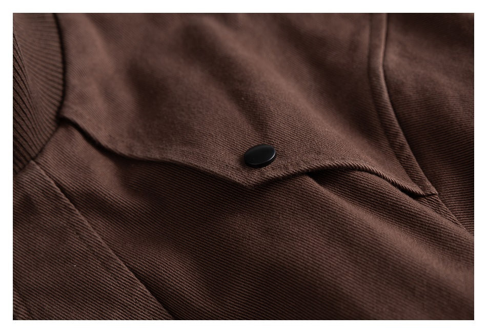 Close-up of a dark brown jacket flap with a black snap button and textured fabric.