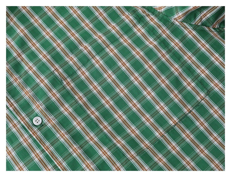 Close-up of the green, brown, and white plaid shirt fabric, button placket, and chest pocket.
