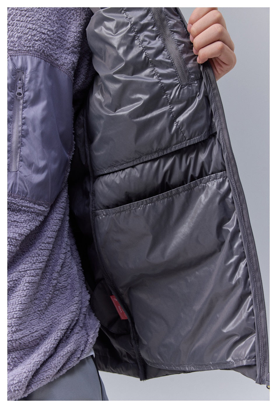 Close-up of the open dark gray vest interior showing glossy lining, an inner pocket and quilted chambers
