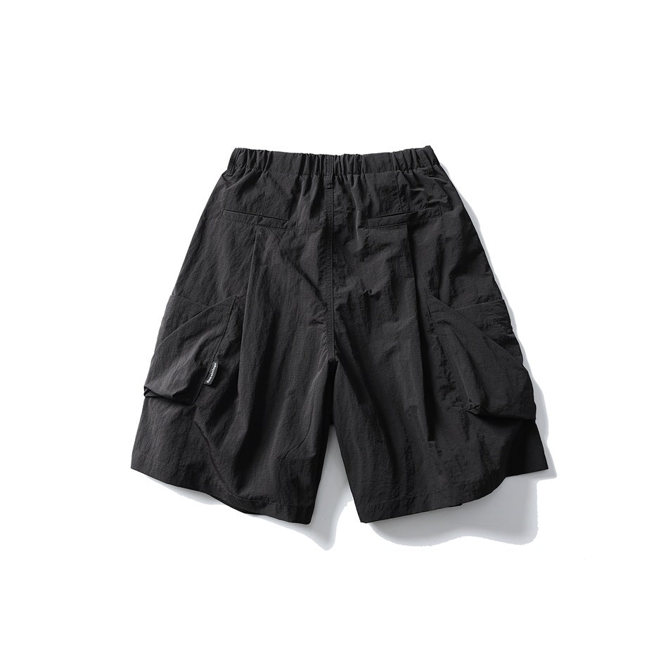 Black cargo shorts shown from the back, with an elastic waistband, two rear welt pockets and large side cargo pockets.