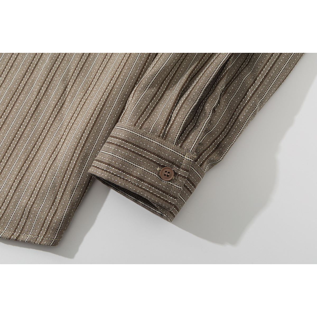 Close-up of a striped shirt cuff with a brown button.