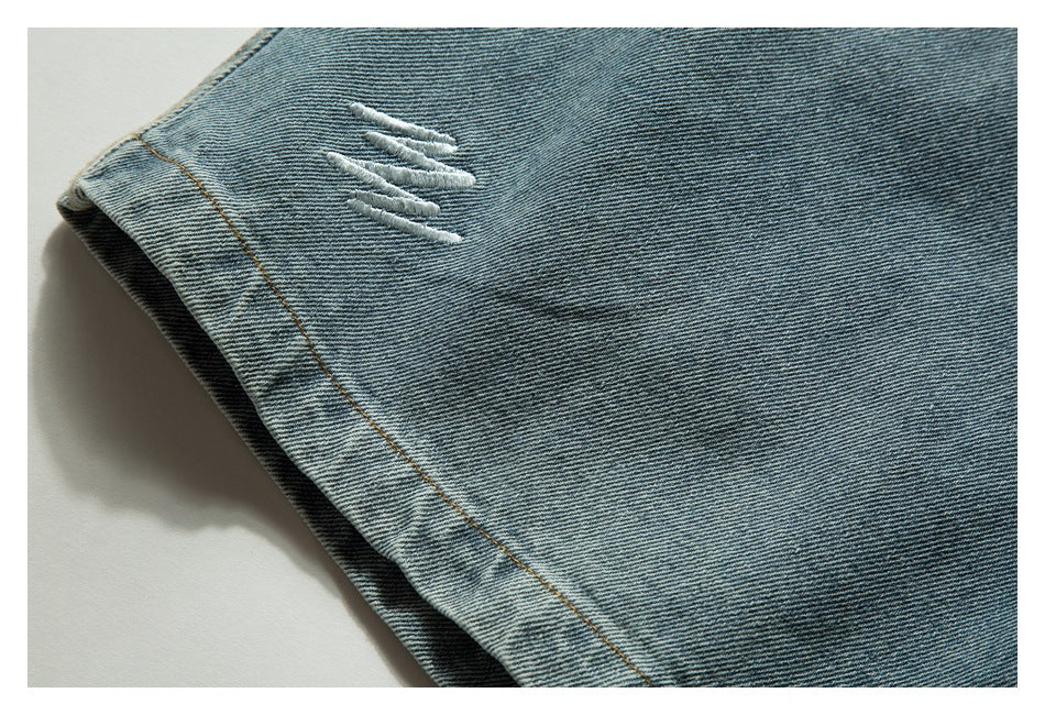 Close-up of light blue denim shorts with a small white distressed detail and tan stitching.