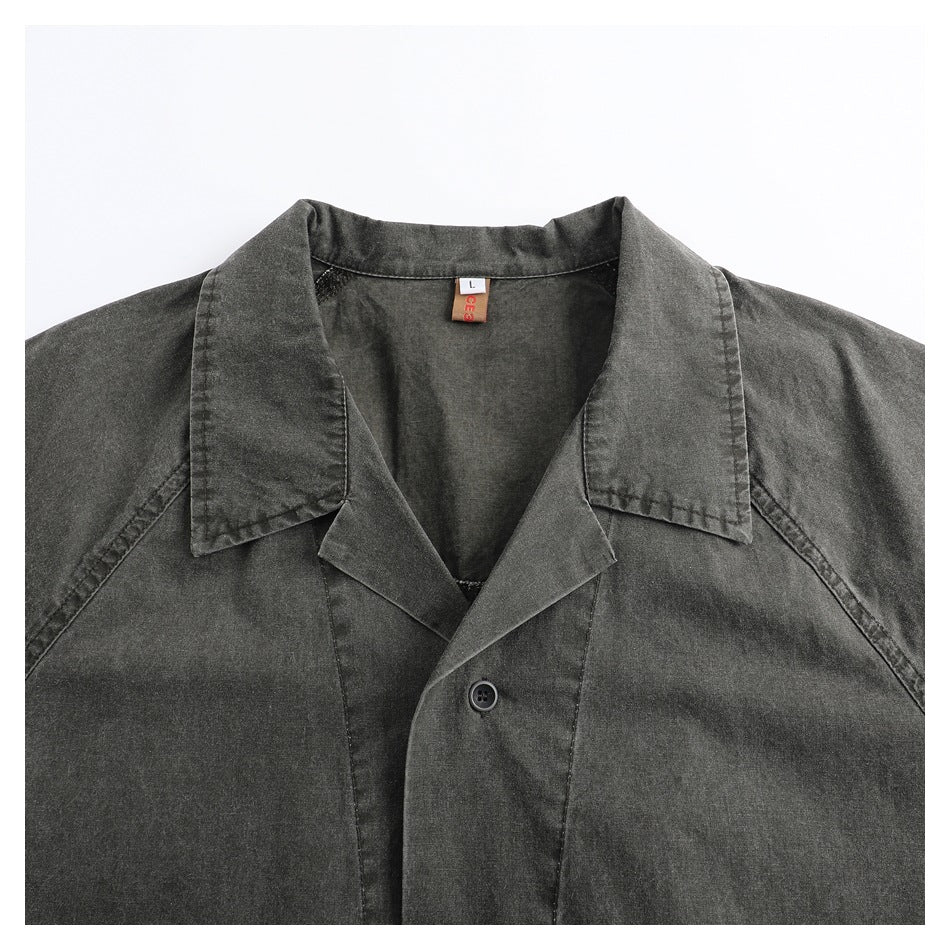Close-up of a charcoal-gray garment's notched collar, button front, and inner size label.