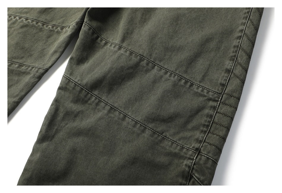 Close-up of dark olive-gray pants showing stitched leg panels and a reinforced side seam.