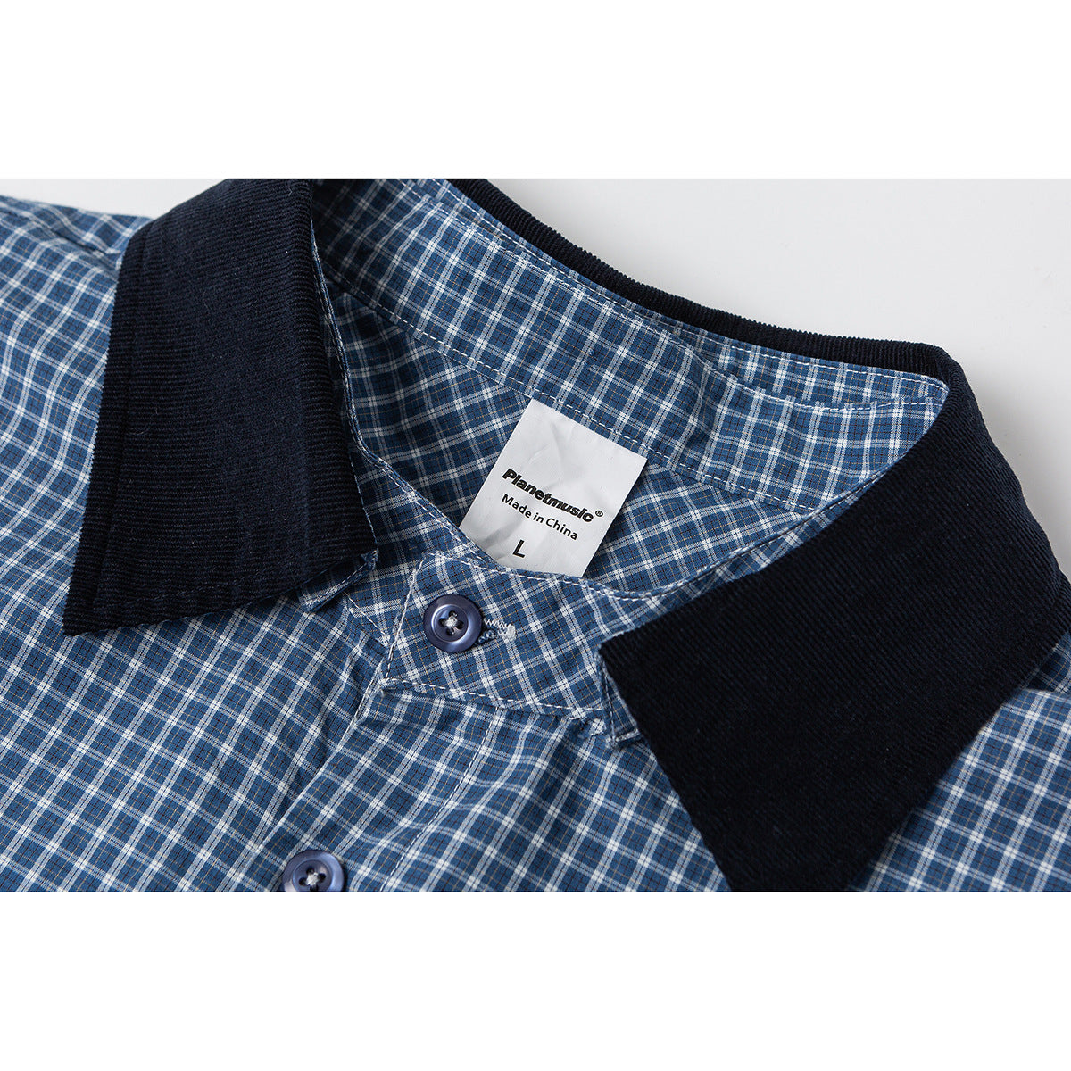 Close-up of a blue plaid shirt with a dark collar, buttons, and a sewn label reading “Made in China” and size L.