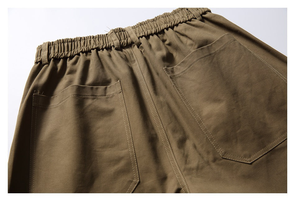 Close-up of the back of khaki trousers with an elastic waistband and two patch pockets.