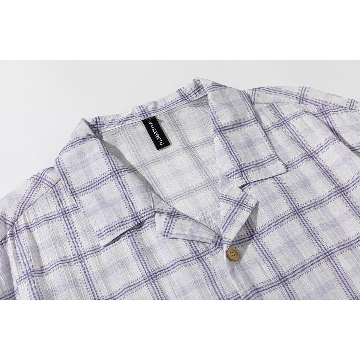 Close-up of a pale lavender and white plaid shirt collar and wooden button.