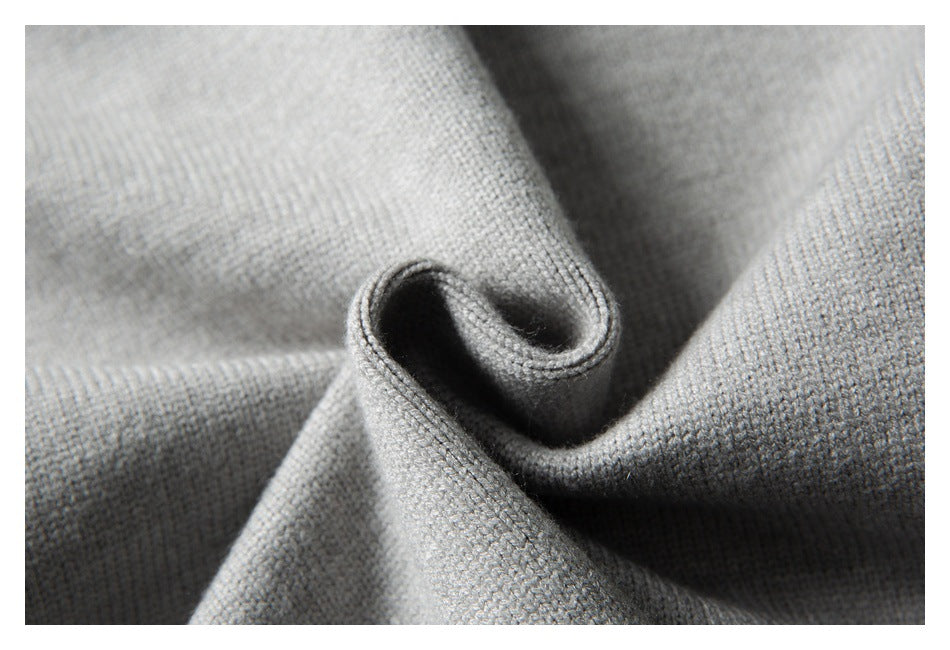 Close-up of gray knit fabric draped into a curl, showing its fine textured weave.